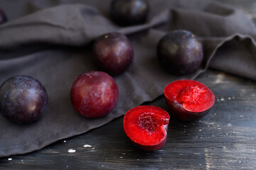 Ripe, juicy plums on a black wooden background. Flat lay.