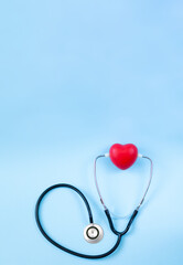 Stethoscope and red heart overhead on light blue backgroung with space for text