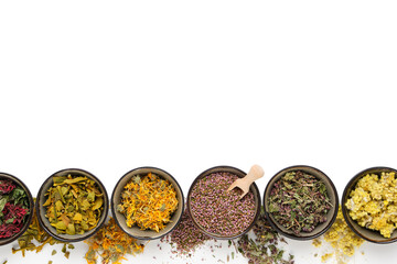 Black bowls of dry medicinal herbs on white background. Top view, flat lay. Alternative medicine. Copy space for text.