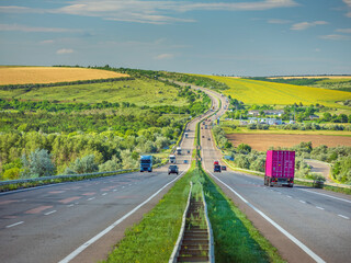 view to highway with turn on hill in summer day with cars and pink container truck under blue sky with copy space