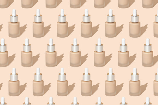 Bright pattern in pastel colors from cosmetic makeup products. A jar of foundation on a beige background. BB, CC cream, liquid fluid for face correction