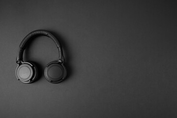 Black wireless headphones isolated on abstract dark background with copy space