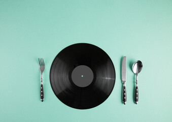Vinyl record and cutlery set on abstract turquoise pastel background with copy space