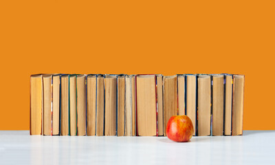 stack of hardback books on white table with red apple. Books stacking. Back to school concept. Copy...