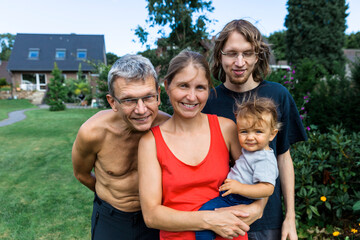 Fototapeta premium Baby girl with her grandfather, her mother and her uncle in the garden