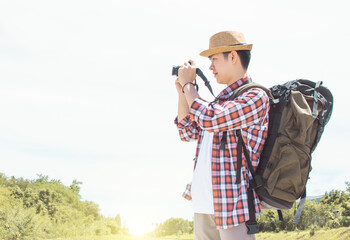 Asian man with backpack using camera while traveling in summer time