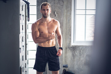 Portrait of Caucasian man showing his biceps muscle at gym fitness studio. muscular strong men workout exercise for better health. people back to normal lifestyle concept with copy space