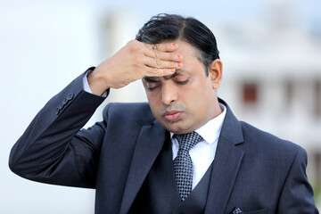 Worried Indian businessman. Young executive in severe tension. Headache. Shocked from bad news.
