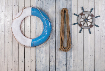 steering wheel and blue lifebuoy on white wooden background