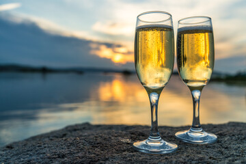 Two glasses of champagne on the shore against the backdrop of sunset. Romantic evening, lovers