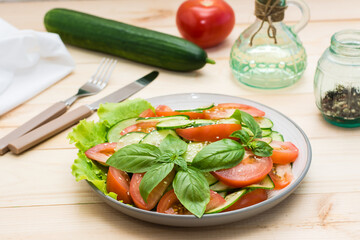 Traditional salad made of slices of cucumber, tomatoes and sesame seeds on a plate and ingredients for cooking on a  table. Vegetarian food