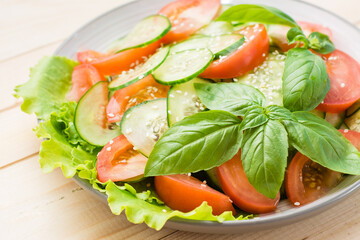 Traditional salad of slices of cucumber, tomatoes and sesame seeds on a plate on a  table. Vegetarian food. Close-up