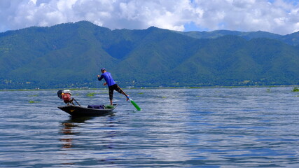 Fototapeta premium A historic fisher on lane inle, standing with one leg on the boat and navigating with the other one.