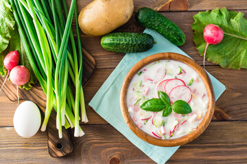 Russian kitchen. Okroshka - cold soup with vegetables and herbs on kefir. Rustic style. Top view