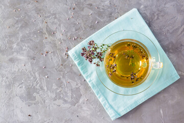 Herbal treatment. Tea with oregano in a glass cup on the table. Relaxing drink. Top view. Copy space