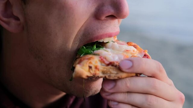 Man eating delicious pizza with seafood cheese and herbs
