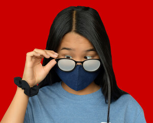 Cute Asian girl with foggy glasses caused by wearing a protective mask