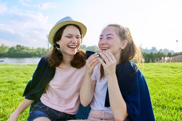 Girlfriends teenagers having fun sitting on grass on sunny summer day