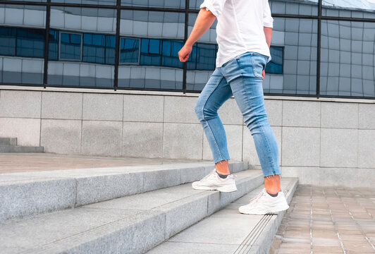 Man with blue geans and white sneaker shoes in stair, go up. Selective focus