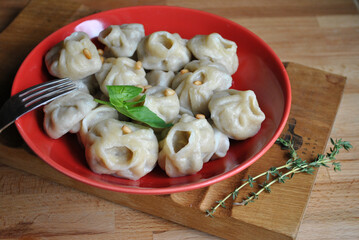 pelmeni with meat and onion on a red plate