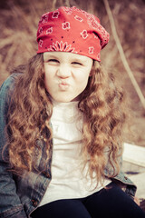 A little girl is dressed with a denim jacket, black boots, and a red bandana, looking like a little rock star.