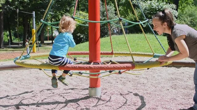 Cute little boy having fun playing on the carousel in the park, beautiful summer sunny day in children playground