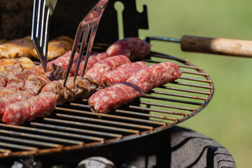 Man turning Balkan food named cevapcici and
chicken roasted on 
barbecue. 