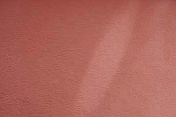 Texture of a pink or red wall, rough surface with a spot of light