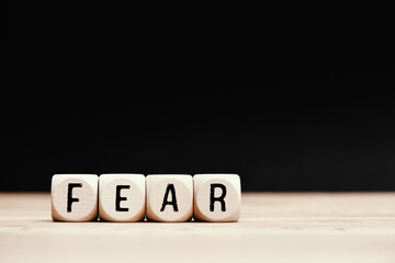 Social topic "Fear" written on wooden cubes with dark background