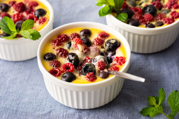 Delicious clafoutis made from white yogurt and berries, raspberries and blueberries, clafoutis in portioned bowls on the table