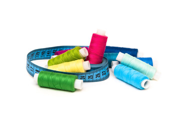 Multicolored threads with needles and tape measure on a white background.
