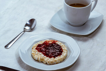 still life con taza de cafe y bizcocho de arroz con mermelada de ciruelas sobre mantel blanco