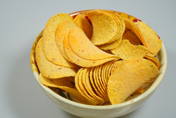 full bowl of yellow potato chips on gray background