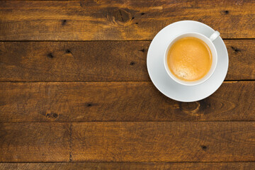 High angle view of coffee in white cup with saucer on old wooden background, close up