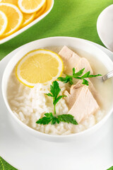 Chicken soup with lemon, egg yolks, parsley and rice. High key. Green background.