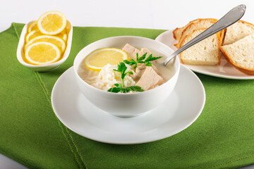 Chicken soup with lemon, egg yolks, parsley and rice. High key. Green background.