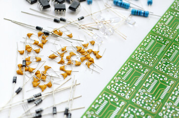 Set of various electronic components arranged near green electronic circuit board on white...