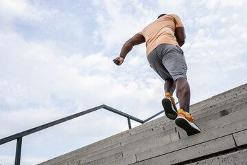 Young black man workout at the city street.He runs up the stairs.Pushing to the limit.