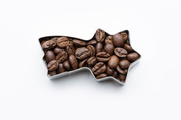 Brown coffee beans filled into a shooting star cookie cutter on white isolated background, Christmas designs, glossy surface