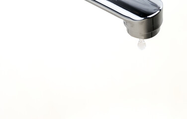 Faucet with a drop of water on a white background. Water leaking and saving. Selective focus.
