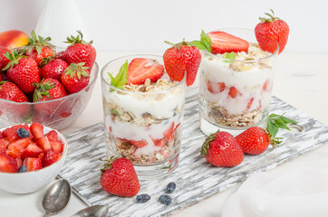 Muesli with yogurt and fresh strawberries on a white background.