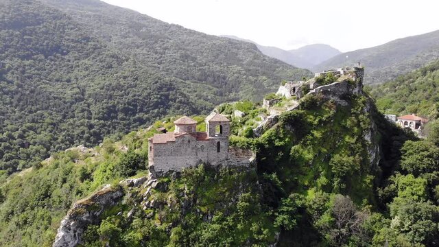 Medieval Fortress on a hill in eastern Europe, Bulgaria. Bulgarian antique and heritage stronghold fortification on a rock. Aerial video of a holy place and monastery. Tourist place with forest. Drone