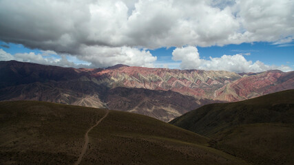 Hiking. Path across the golden meadow, valley and mountains. Aerial view of the popular landmark mountain Hornocal. Its beautiful texture and colorful rocks under a dramatic sky.