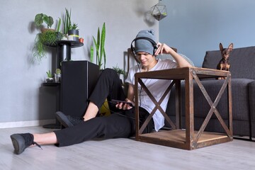Teenage boy hipster in headphones with smartphone listening to music