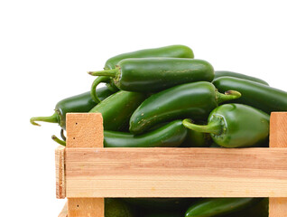 bunch of fresh green chili peppers in wooden crate on a white background