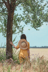 woman in yellow sundress walking by wheat field