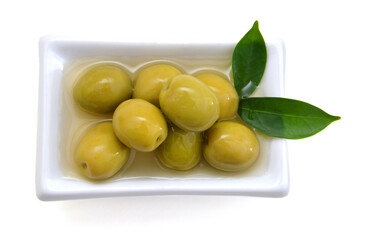 pickled green olives in a bowl and olive tree branch on a white background