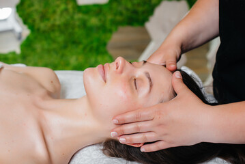 Obraz na płótnie Canvas A young pretty girl is enjoying a professional head massage at the Spa. Body care. Beauty salon