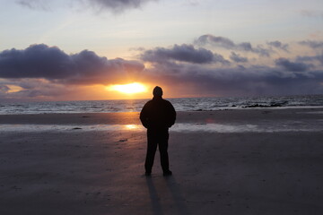 man walking on the beach at sunset, outer hebrides, scotland