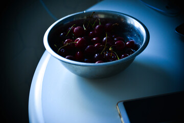 Red ripe cherries with twigs in a Cup and on the table
